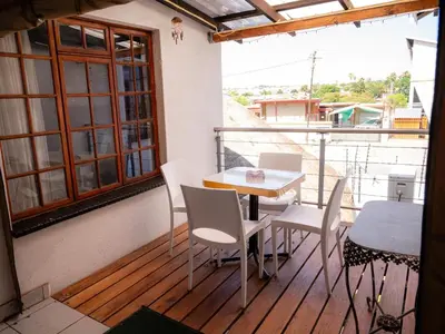 a balcony with a table and chairs and a window at Sleepers Villa Guesthouse in Polokwane