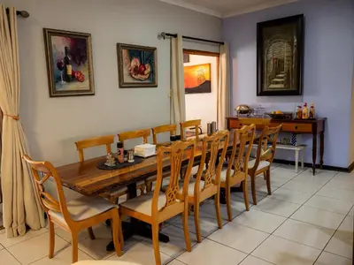 a dining room with a wooden table and chairs at Sleepers Villa Guesthouse in Polokwane
