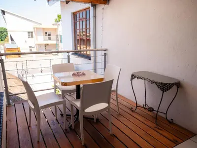 a balcony with a table and chairs on a deck at Sleepers Villa Guesthouse in Polokwane
