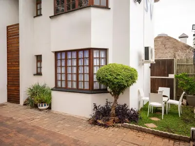 a white house with a tree in the yard at Sleepers Villa Guesthouse in Polokwane