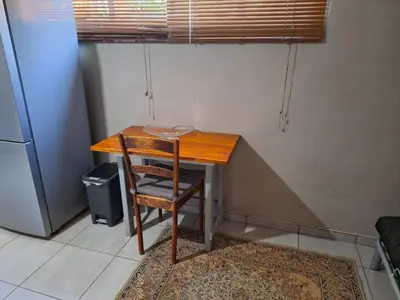 a wooden table with a chair next to a refrigerator at 1@Kruger in Mokopane