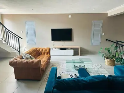 a living room with couches and a flat screen tv at Angel’s Nest Nelspruit in Nelspruit