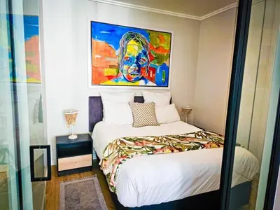 a bedroom with a bed with a painting on the wall at Luxurious, affordable Ellipse apartment in Midrand