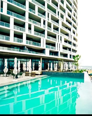 a swimming pool with umbrellas and chairs and a building at Luxurious, affordable Ellipse apartment in Midrand