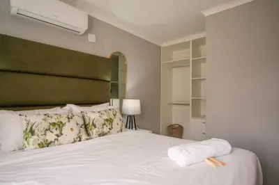 a bedroom with a white bed with a green headboard at Masana at Homely Escape in Phalaborwa