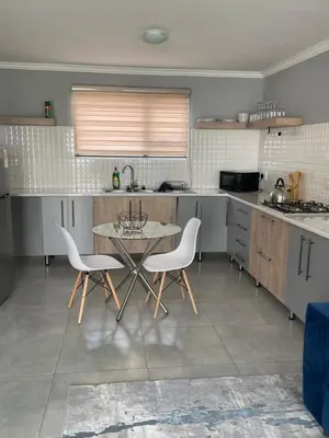a kitchen with a table and two white chairs at Masana at Homely Escape in Phalaborwa