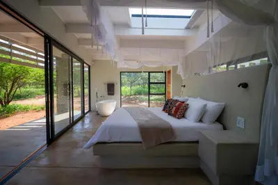 a bedroom with a large bed and a bath tub at Ungava Retreat in Marloth Park