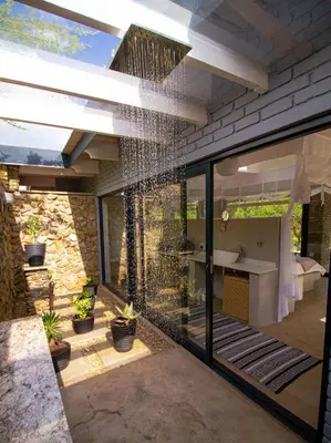 a glass house with a bathroom and a sink at Ungava Retreat in Marloth Park