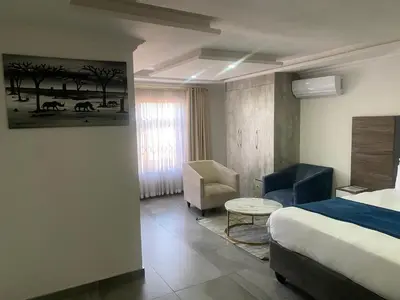 a hotel room with a bed and a chair at Hotel El Infinito in Kempton Park