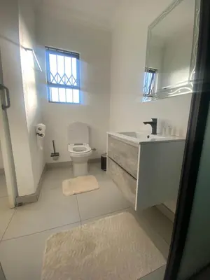 a bathroom with a toilet and a sink and a mirror at Hotel El Infinito in Kempton Park