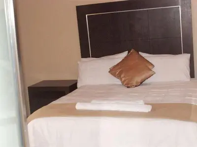 a bed with a brown pillow and white pillows at DZUVHA VILLAGE INN in Thohoyandou