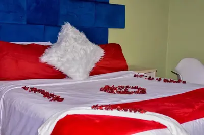 a bed with red and white pillows and red decorations at Mashaka Ashu Lodge in Dzindi