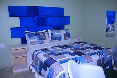 a bedroom with a bed with a blue headboard at Mashaka Ashu Lodge in Dzindi