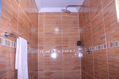 a bathroom with a shower with wooden tiles at Mashaka Ashu Lodge in Dzindi
