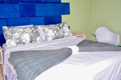 a bedroom with a bed with a blue headboard at Mashaka Ashu Lodge in Dzindi