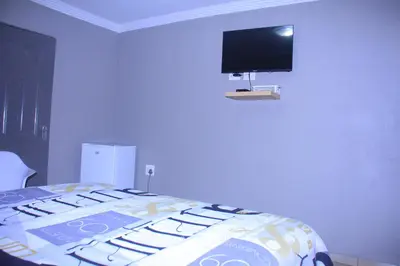 a bedroom with a bed with a tv on the wall at Mashaka Ashu Lodge in Dzindi