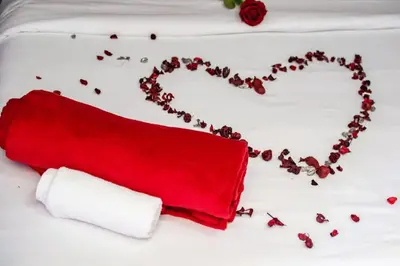 a bed with a red pillow and a heart made of coffee beans at Mashaka Ashu Lodge in Dzindi