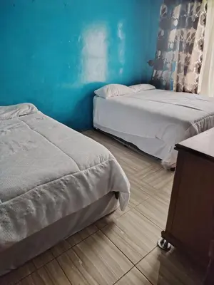 two beds in a room with blue walls and wooden floors at Molata Rabs in Polokwane