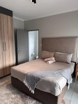 a bedroom with a large bed with a pink pillow on it at Secure 1 Bedroom Apartment in Midrand, Waterfall City - Lock Up and Go - Free WIFI and Parking - 9 Elizabeth Place in Midrand