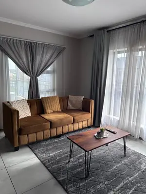 a living room with a couch and a coffee table at Secure 1 Bedroom Apartment in Midrand, Waterfall City - Lock Up and Go - Free WIFI and Parking - 9 Elizabeth Place in Midrand