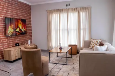 a living room with a couch and a brick wall at Secure 1 Bedroom Apartment in Midrand, Waterfall City - Lock Up and Go - Free WIFI and Parking - 8 Elizabeth Place in Midrand