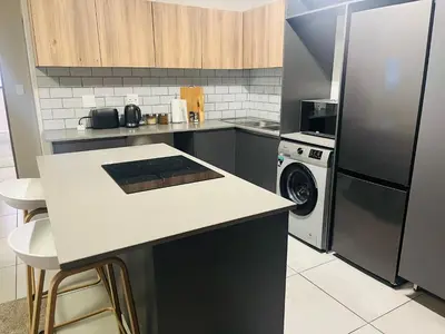 a kitchen with a refrigerator and a washer and dryer at 10 Elizabeth Place - Beautiful self catering 2 bedroom unit next to Kyalami Racetrack with free WiFi swimming pool gym and restaurant - Perfect for a small family in Midrand Waterfall in Midrand