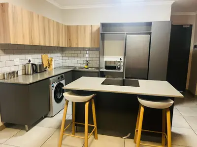 a kitchen with a sink and a counter with stools at Spacious 2 Bedroom Apartment in Midrand, Waterfall City - Business and Family friendly - 11 Elizabeth Place in Midrand