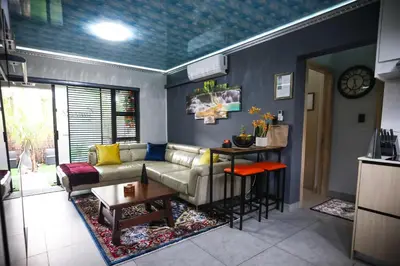 a living room with a couch and a table at Air-Conditioned, Self-Catering Apartment with Heated Pool Near OR Tambo International Airport in Benoni