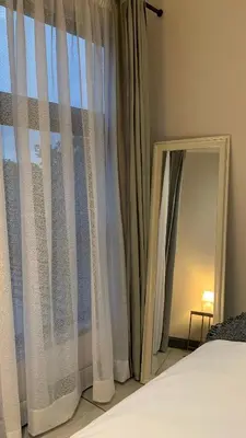 a mirror sitting next to a window next to a bed at Forest Hill in Pretoria