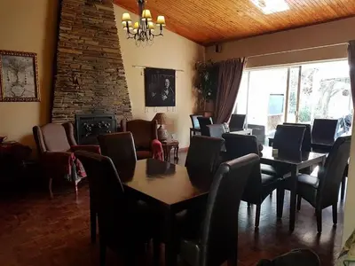a dining room with tables and chairs and a fireplace at 40 on Ilkey B&B in Pretoria