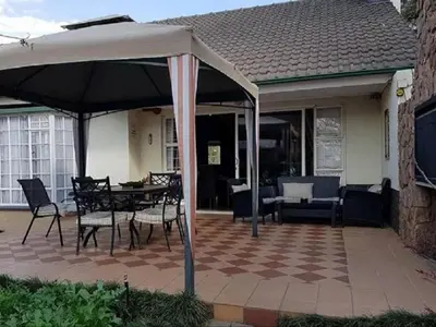 an umbrella on a patio with a table and chairs at 40 on Ilkey B&B in Pretoria