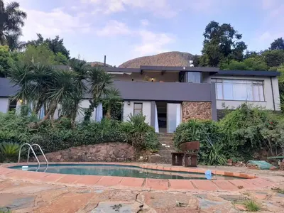 a house with a swimming pool in front of it at Dam House Lodge in Hartbeespoort