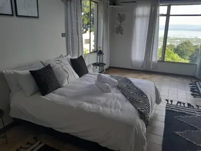 a large bed in a bedroom with a large window at Dam House Lodge in Hartbeespoort