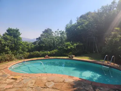 a small swimming pool in a yard with trees at Dam House Lodge in Hartbeespoort