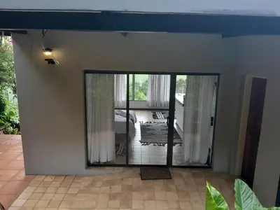 a living room with a large glass door to a patio at Dam House Lodge in Hartbeespoort