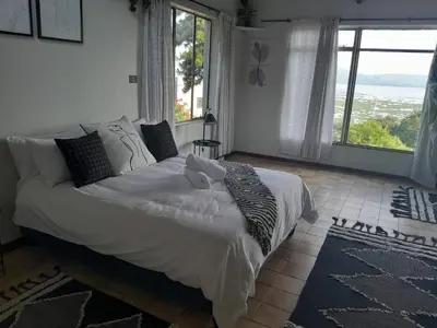 a bedroom with a large bed with a large window at Dam House Lodge in Hartbeespoort