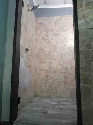 a bathroom with a stone wall and a shower at Dam House Lodge in Hartbeespoort
