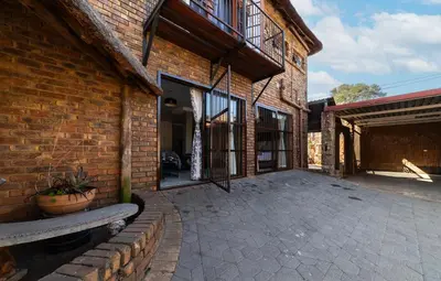 a brick building with a patio in front of it at Thatch Haven Guesthouse in Centurion