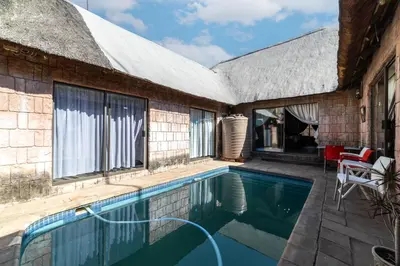 a house with a swimming pool next to a building at Thatch Haven Guesthouse in Centurion