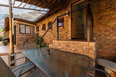 a patio with a glass table on a brick wall at Thatch Haven Guesthouse in Centurion