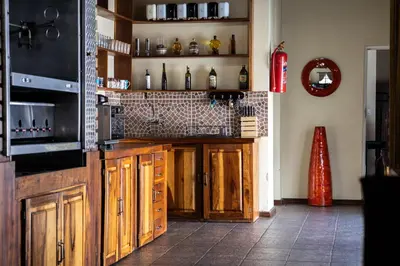 a kitchen with wooden cabinets and a wall with bottles at Thatch Haven Guesthouse in Centurion