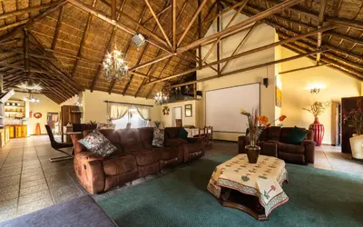 a large living room with leather couches and a table at Thatch Haven Guesthouse in Centurion