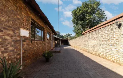 a brick wall with a bench next to a building at Thatch Haven Guesthouse in Centurion
