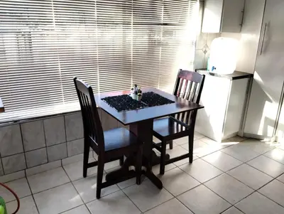 a kitchen with a table and two chairs and a refrigerator at Turquoise View Guesthouse in Middelburg
