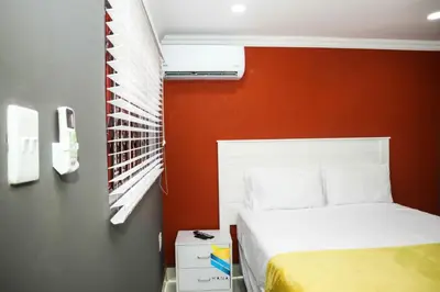 a bedroom with a bed and an orange wall at HANA GUESTHOUSE in Pretoria