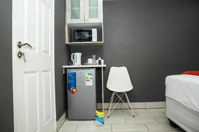 a small refrigerator in a room with a white chair at HANA GUESTHOUSE in Pretoria