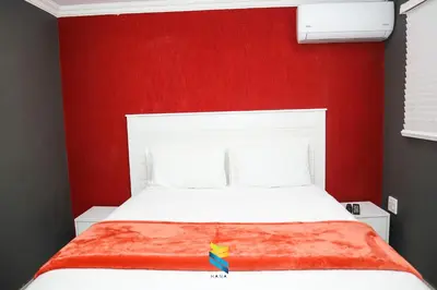 a bedroom with a red wall and a white bed at HANA GUESTHOUSE in Pretoria