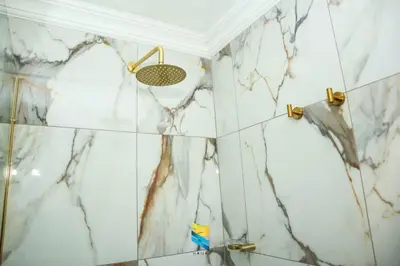 a bathroom with white marble walls and a shower at HANA GUESTHOUSE in Pretoria