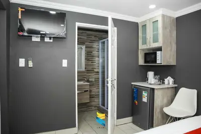 a room with a television and a kitchen with a refrigerator at HANA GUESTHOUSE in Pretoria