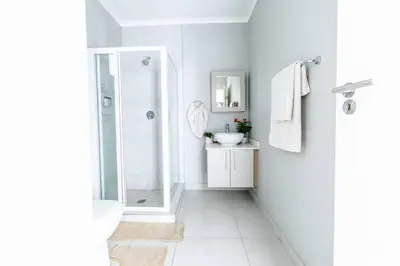 a white bathroom with a shower and a sink at Central Serenity @Midrand in Midrand